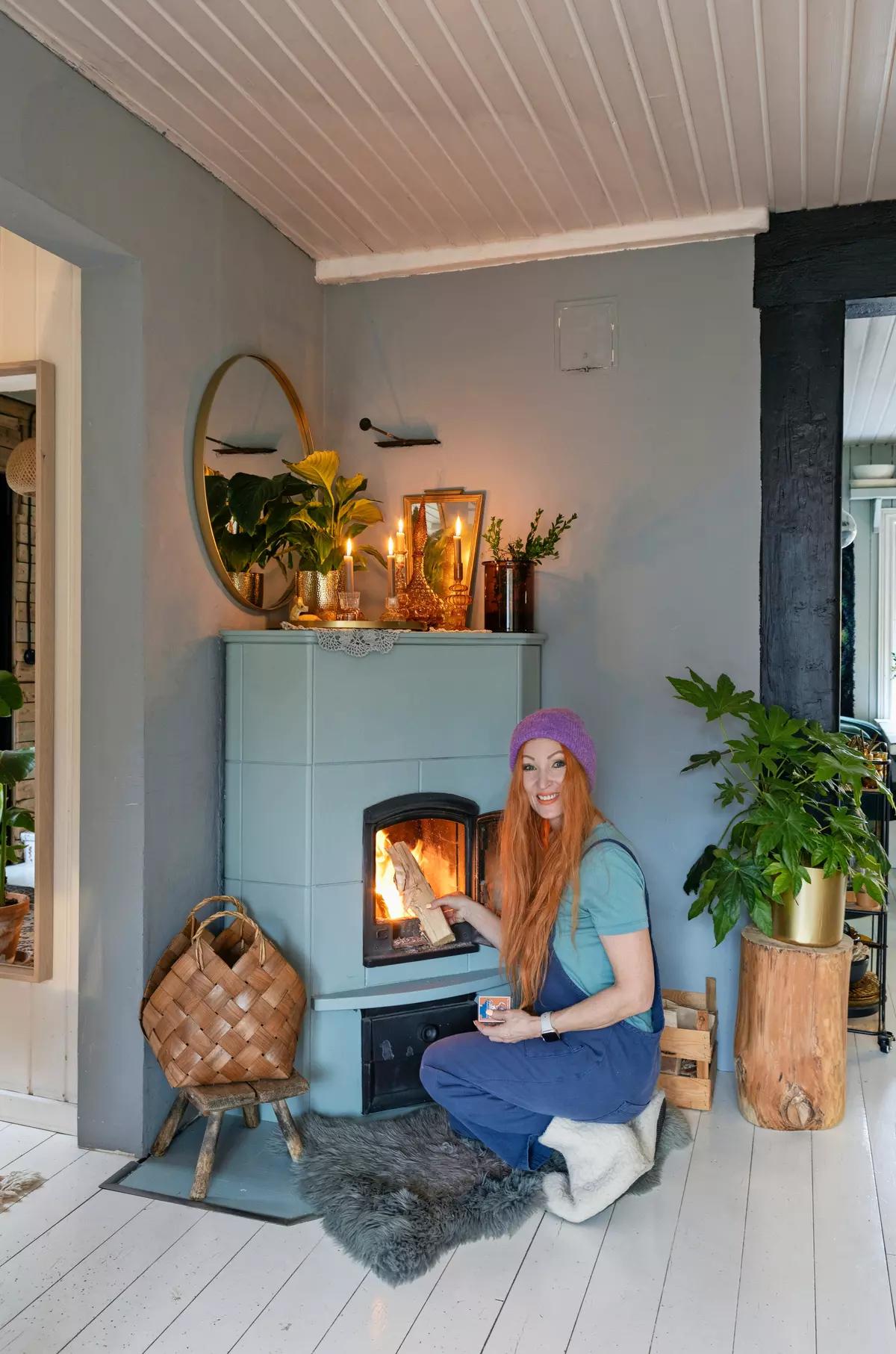 Женщина кладет дрова в старую печь