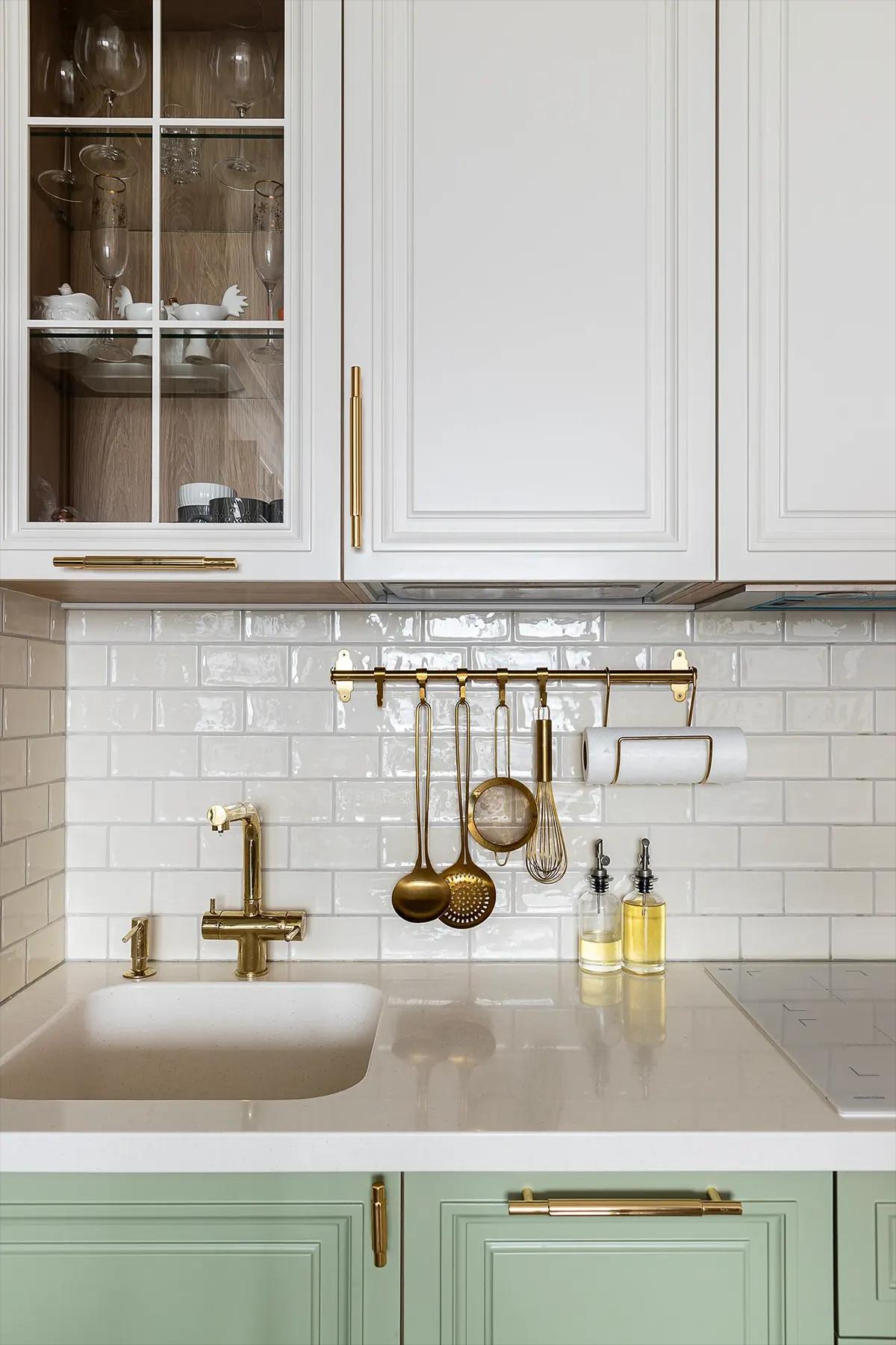 Белые кухонные шкафы и позолоченная кухонная утварь
