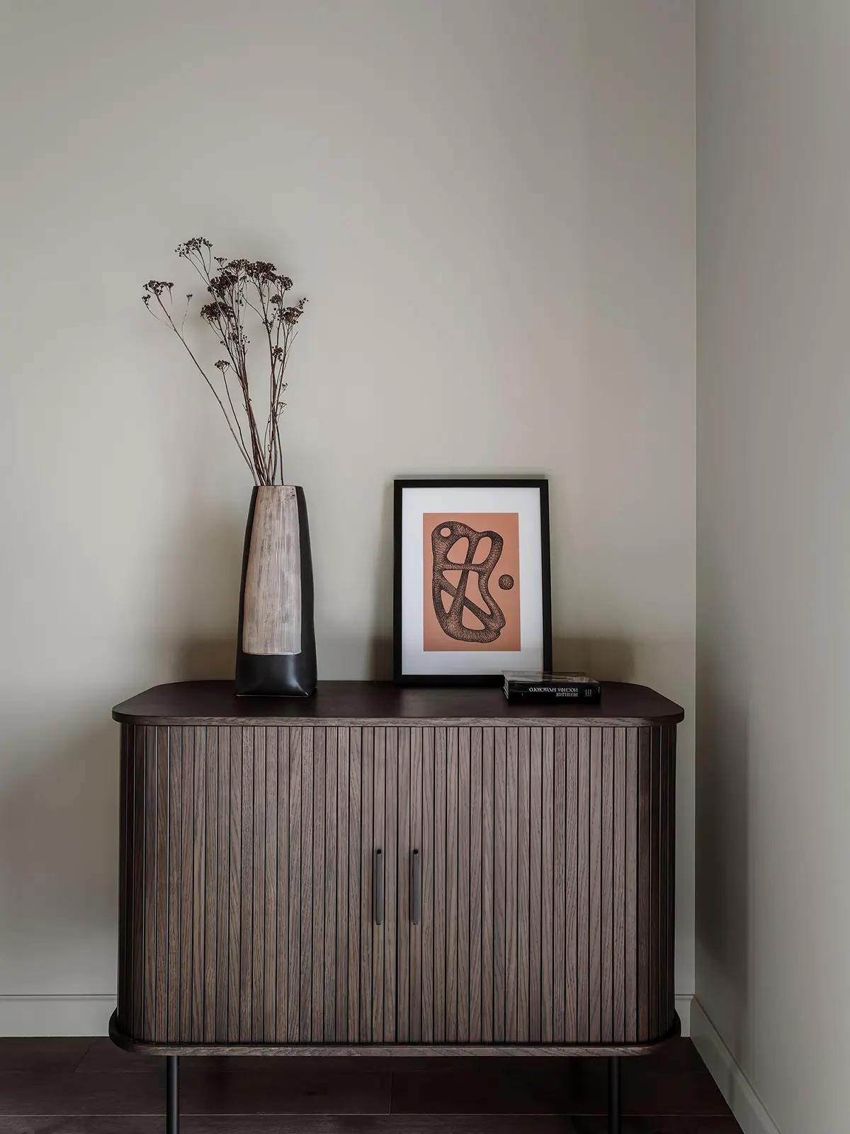 Современный деревянный комод с вазой сухоцветов и абстрактной картиной