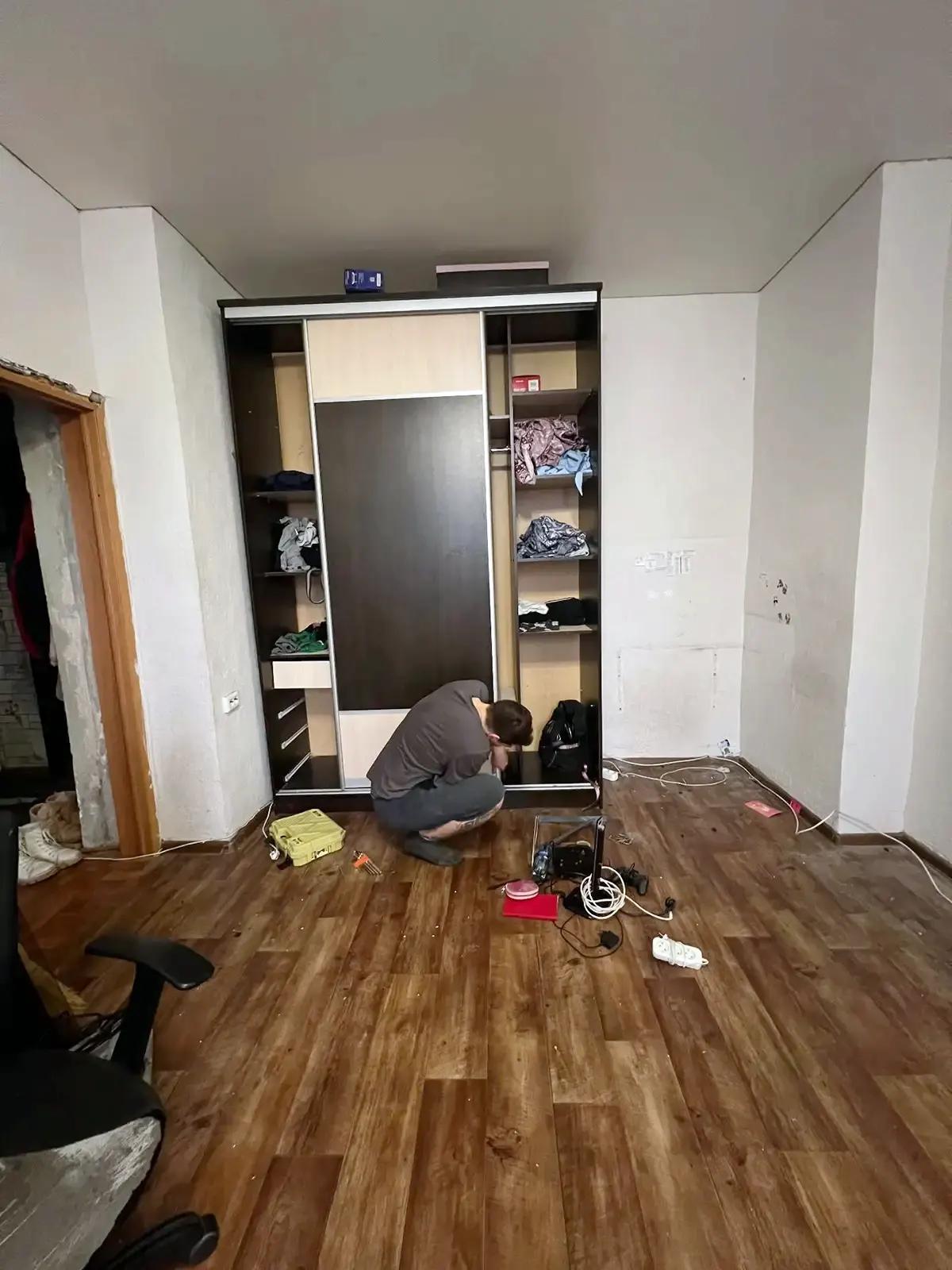 Мужчина демонтирует шкаф в квартире