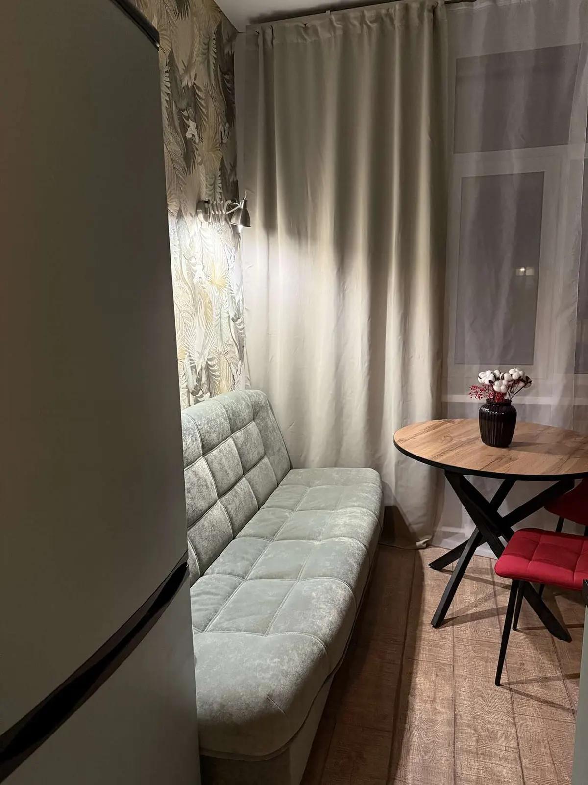 Зеленый диван на кухне, деревянный стол и красный стул