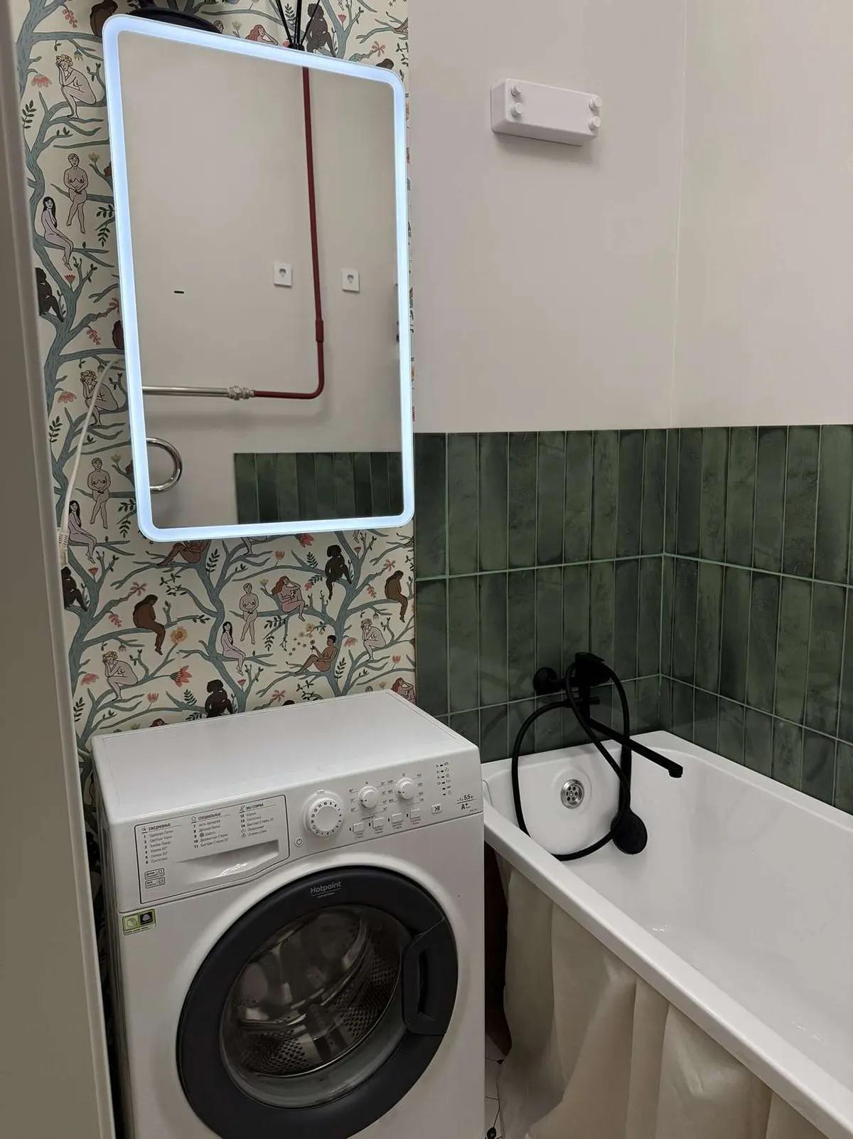 Ванная с подсвеченным зеркалом, обоями "Женщины в деревьях", зелёной плиткой и стиральной машиной