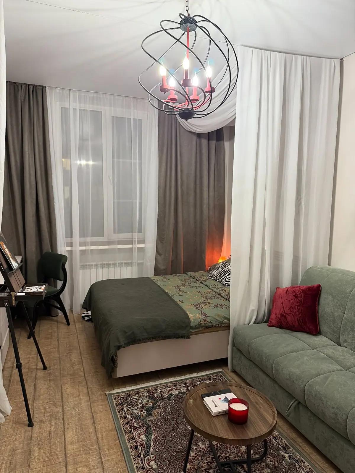 Уютная комната с кроватью и диваном, разделенная белой шторой