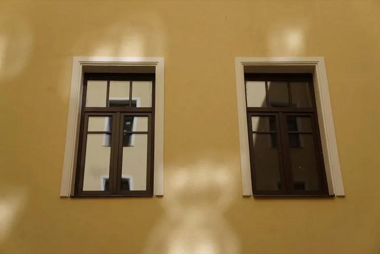 Желтый фасад здания с двумя окнами