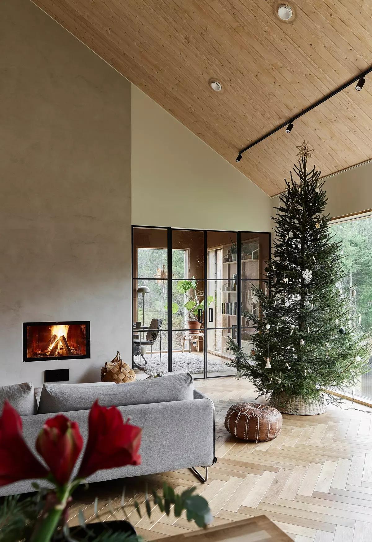 Светлая гостиная, украшенная к Рождеству с камином и высокой елкой