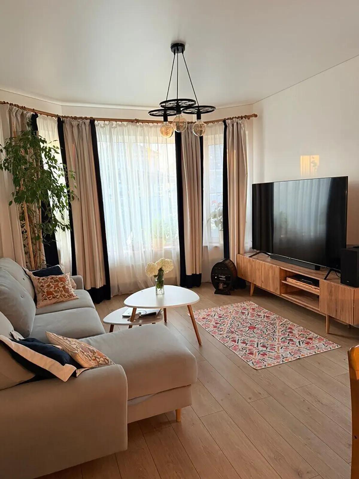 Гостиная с серым угловым диваном, журнальным столиком с цветами и телевизором на тумбе