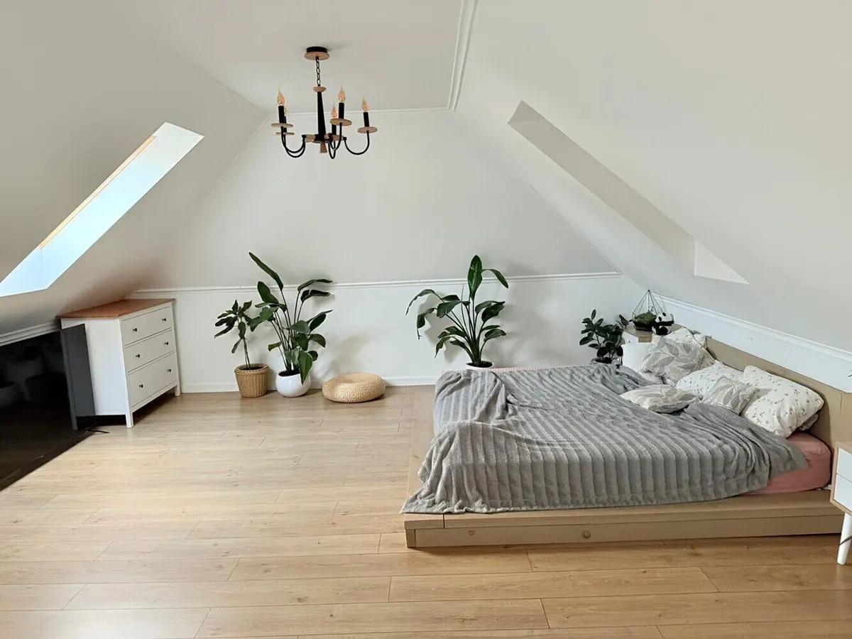 Мансардная спальня с белыми стенами и кроватью на платформе