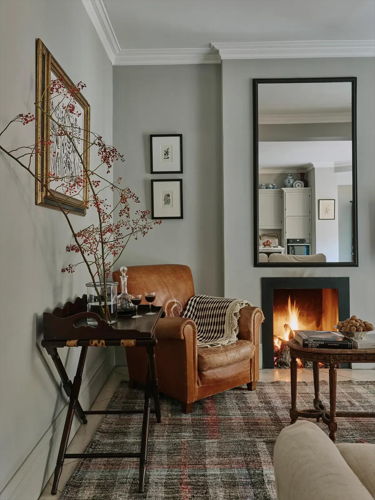 Кожаное кресло у горящего камина с пледом, столиком с вином