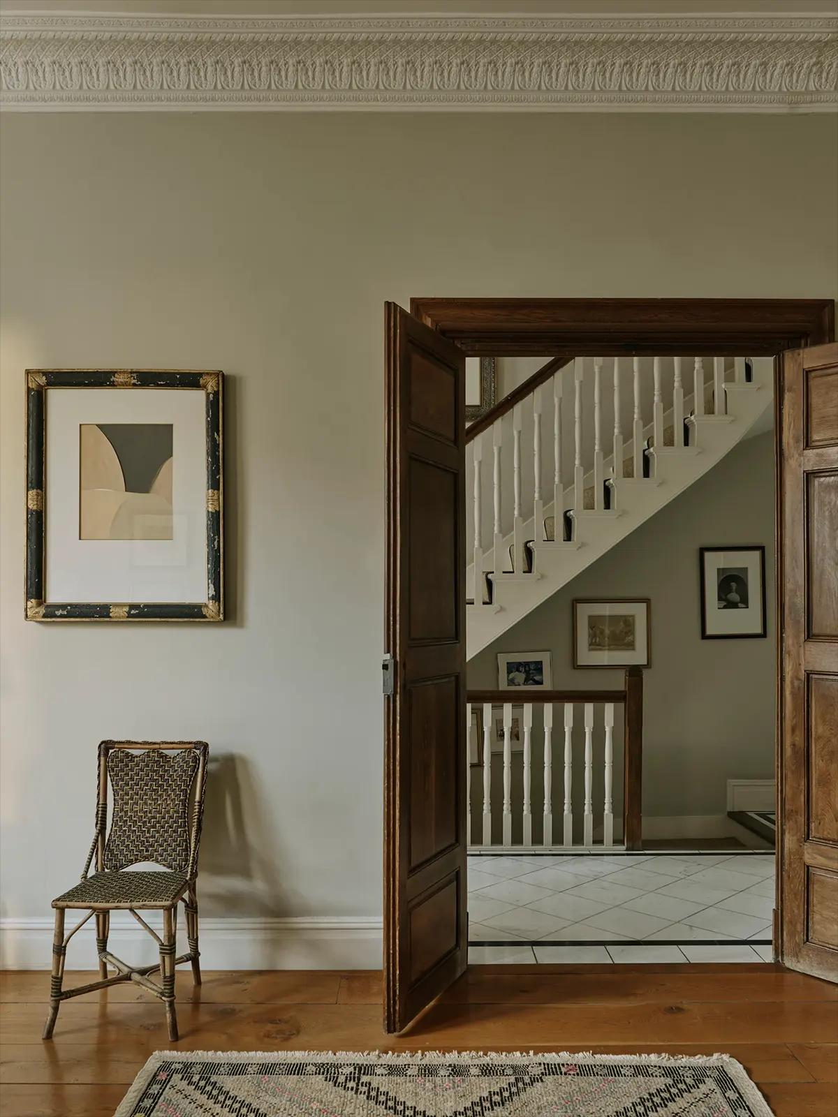 Открытая деревянная дверь в холле с видом на белую лестницу