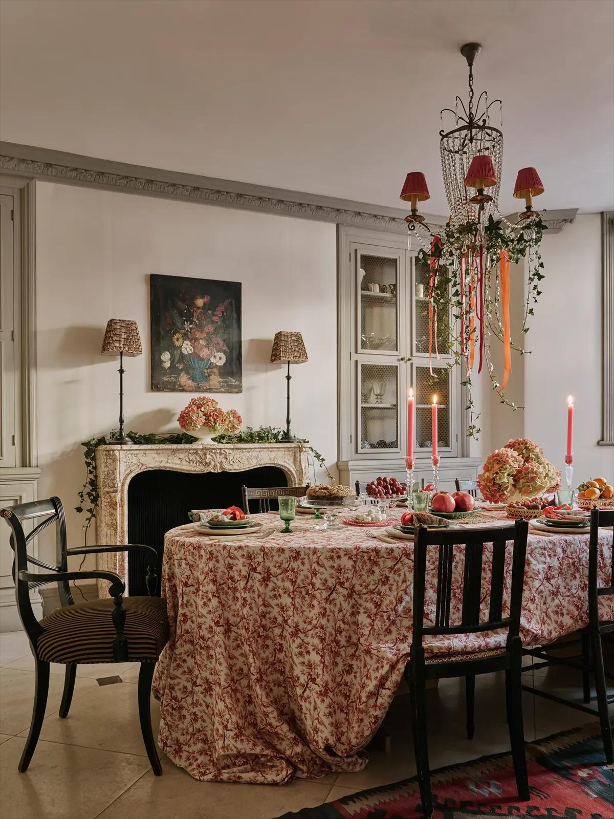 Праздничная столовая с круглым столом, розовой скатертью в цветок, розовыми свечами и люстрой с плющом