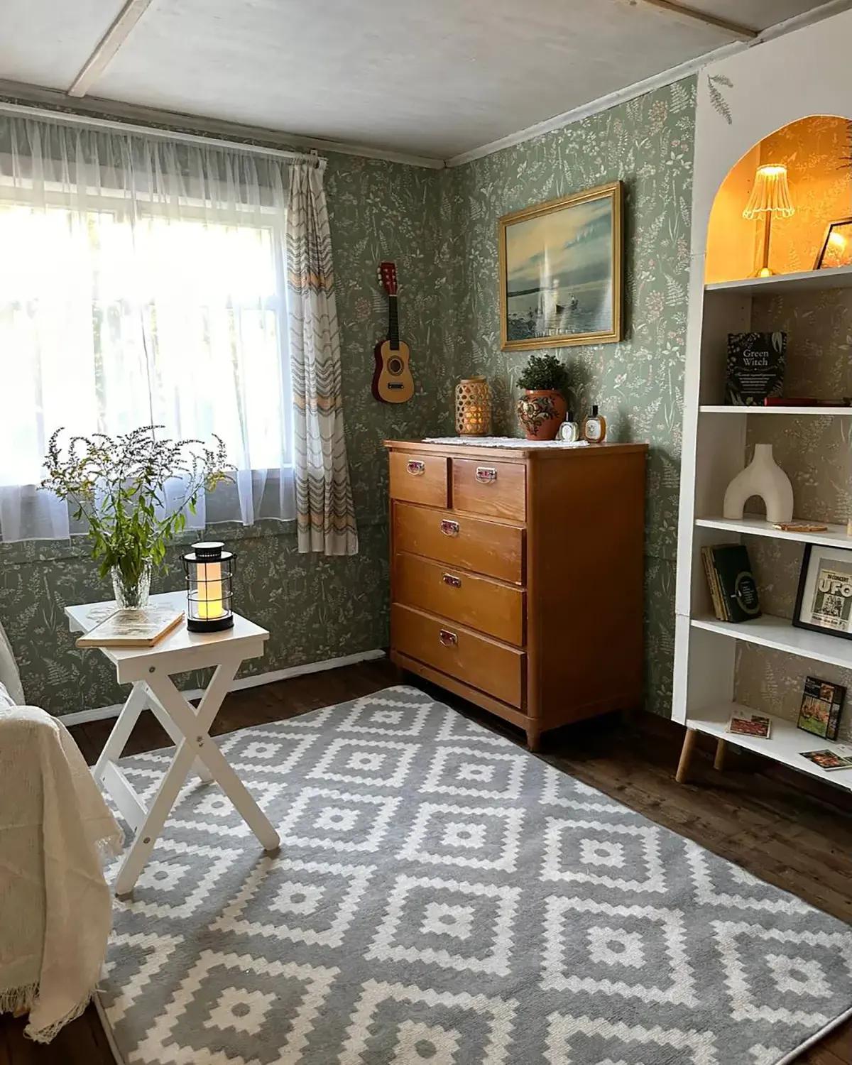 Гостиная после ремонта. В комнате светло-зеленые обои, отреставрированный комод, серый ковер с геометрическим узором и предметы декора (картина и мини-гитара на стене)