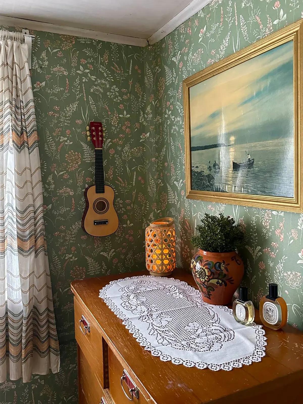 Картина в позолоченной рамке с пейзажем и маленькая гитара на стене в гостиной