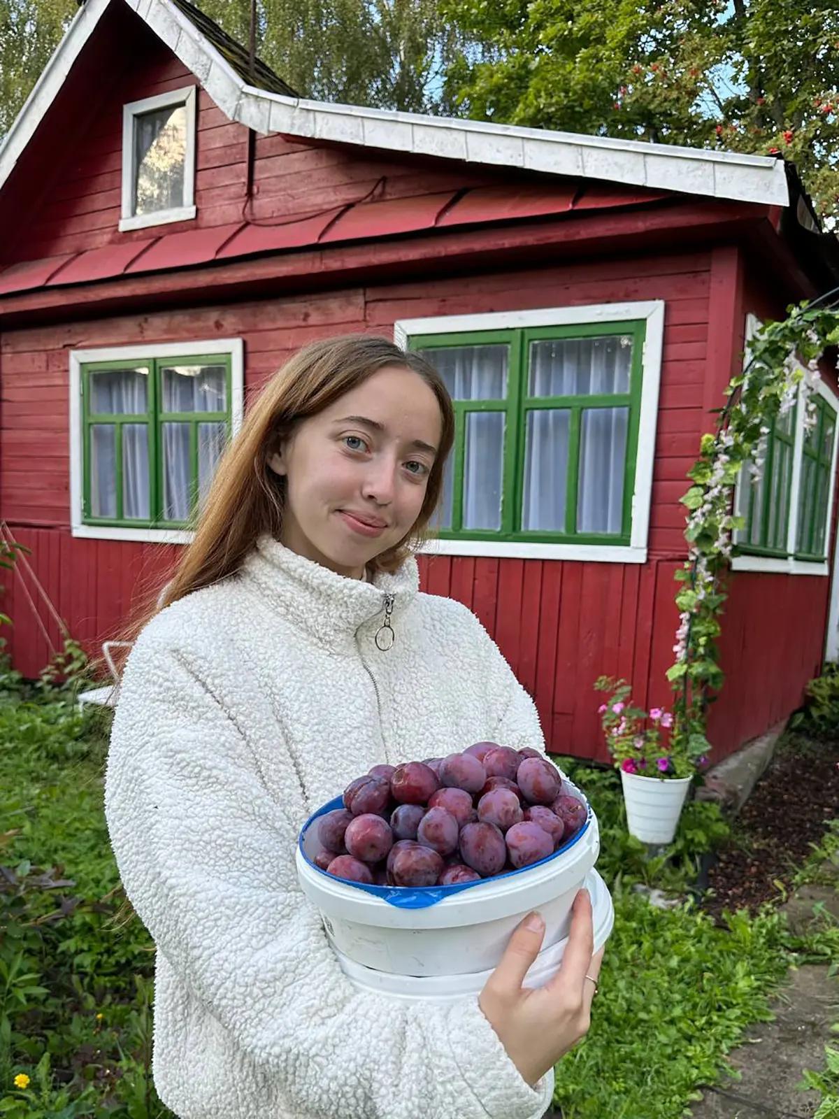 Виктория (хозяйка дома) с урожаем в руках на фоне своей дачи