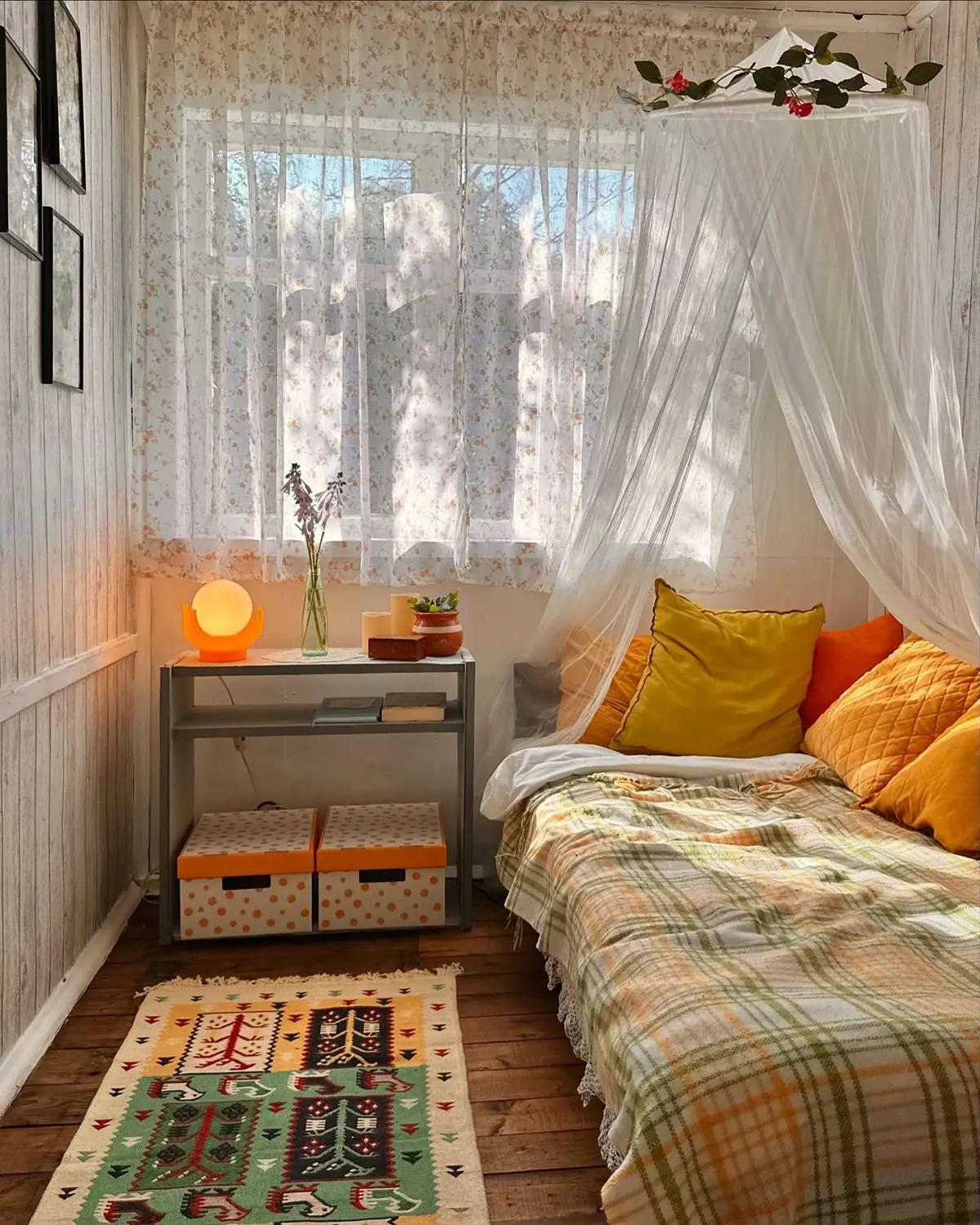 Уютная спальня после ремонта в доме с ярким постельным бельем, ковриком и другими деталями декора 