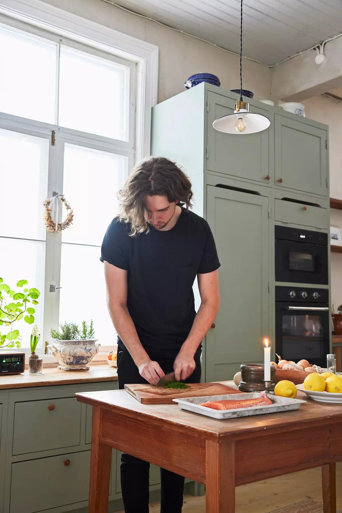 Мужчина режет зелень на разделочной доске