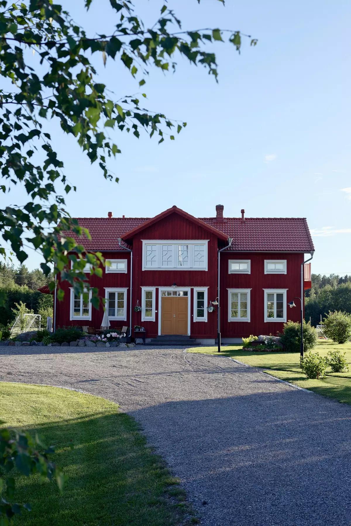 Красный деревянный дом с белыми окнами, жёлтой дверью, гравийной дорожкой и зелёным садом