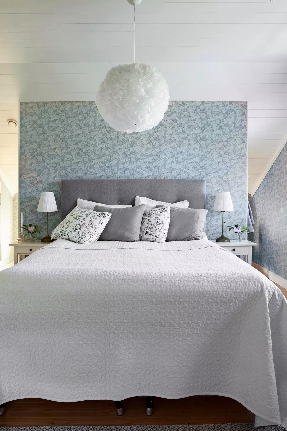 Спальня с серым изголовьем, подушками, прикроватными лампами и цветочными голубыми обоями