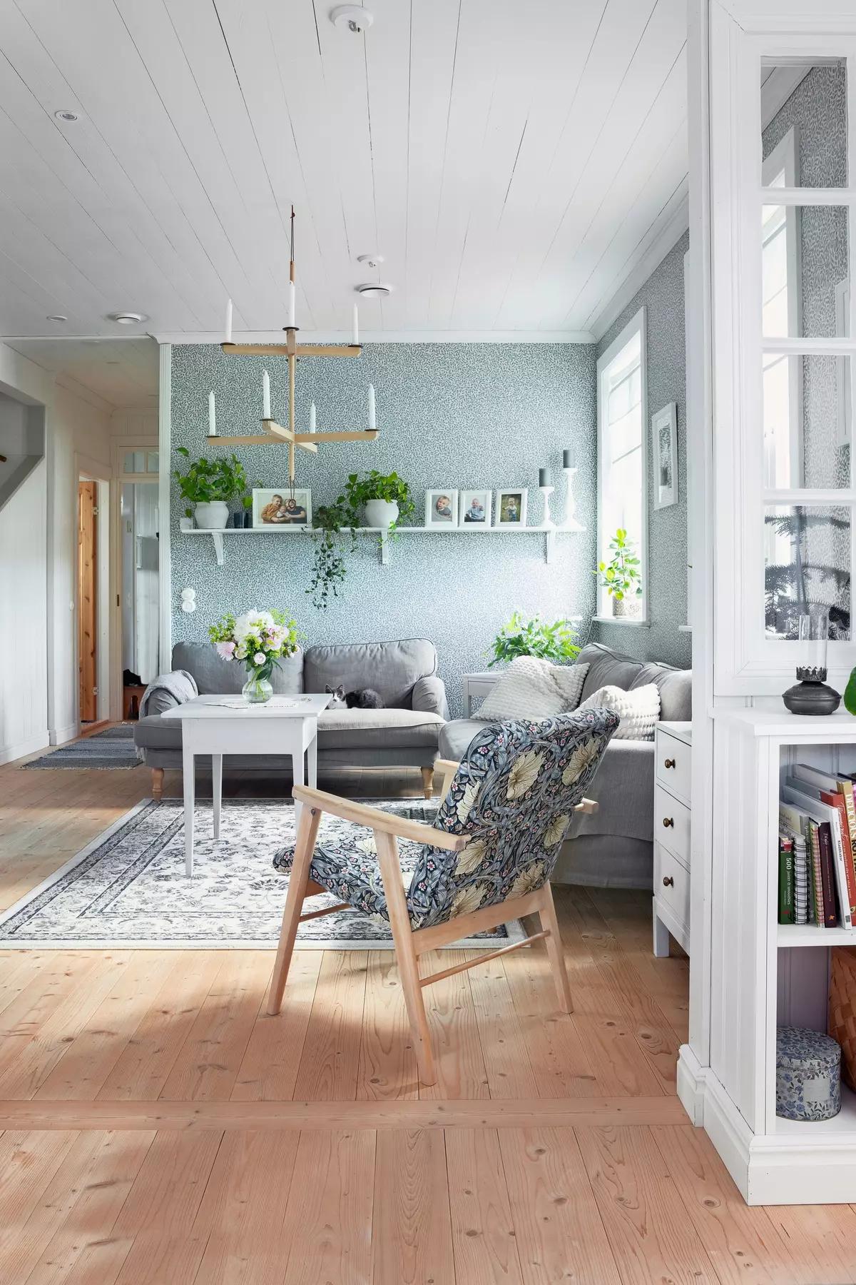 Уютная финская гостиная с серым диваном, узорчатым креслом, растениями на полке и журнальном столе