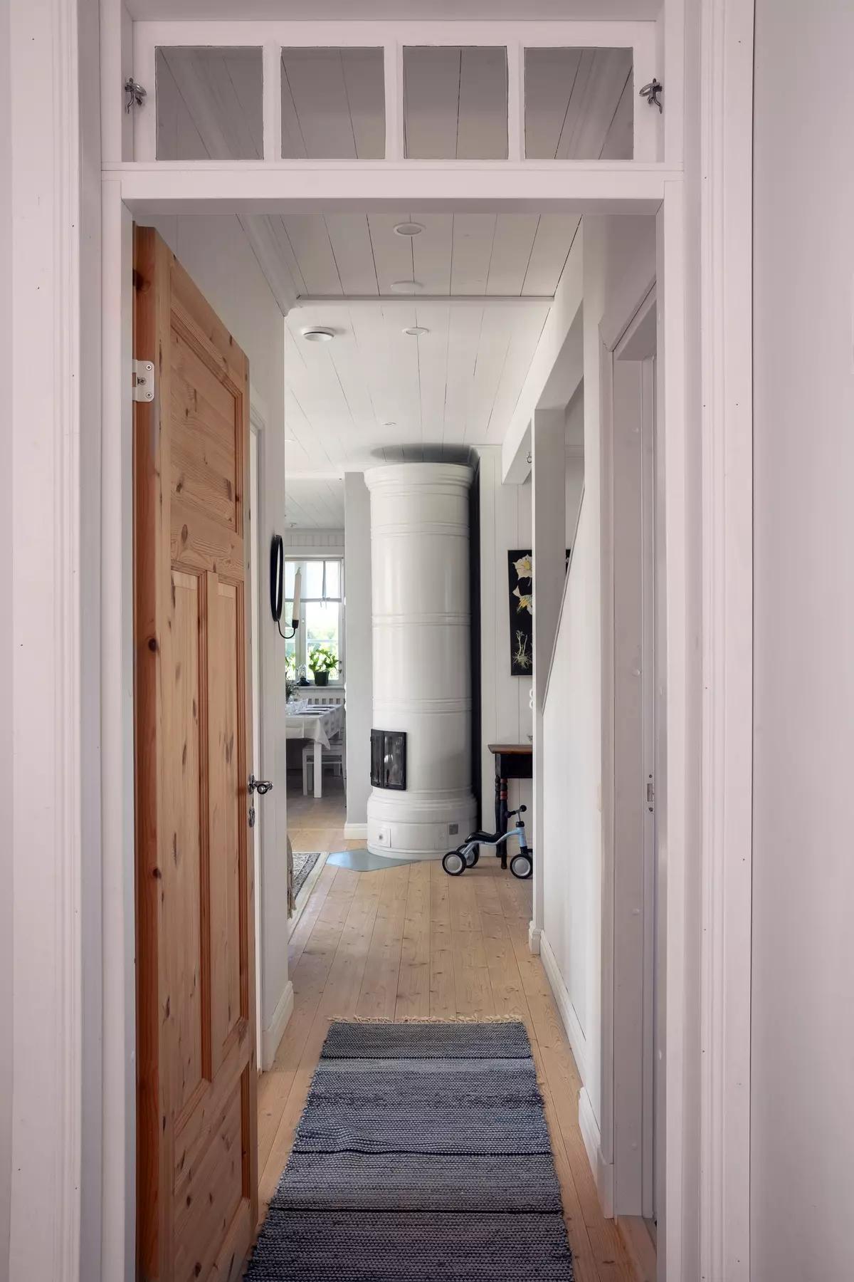 Вид через деревянную дверь в коридор с ковриком и белой печью