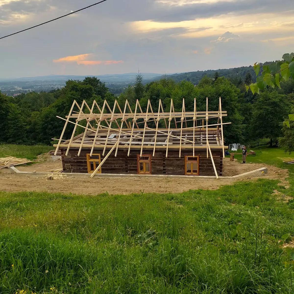 Деревянный сруб с недостроенной крышей на фоне заката