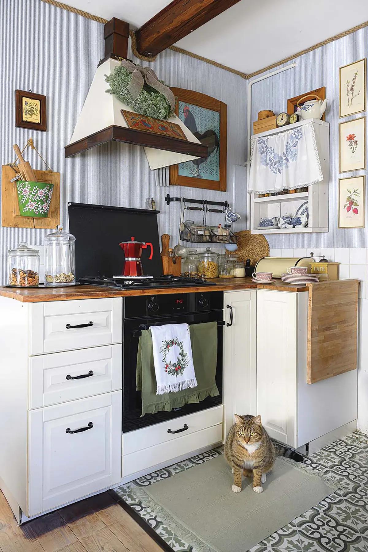 Кухонный уголок с белыми шкафами, плитой и красной гейзерной кофеваркой