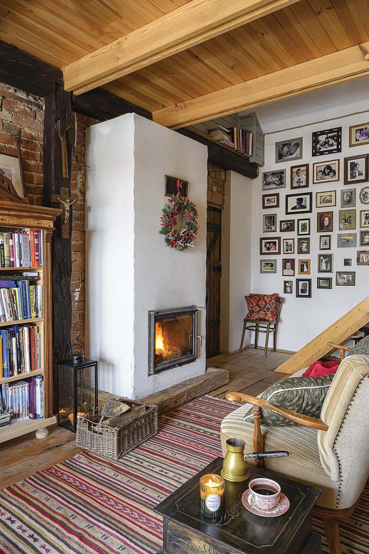 Теплая зона отдыха с кирпичной стеной, горящим камином, книжными полками, галереей семейных фото на стене, креслом и журнальным столиком с кофе