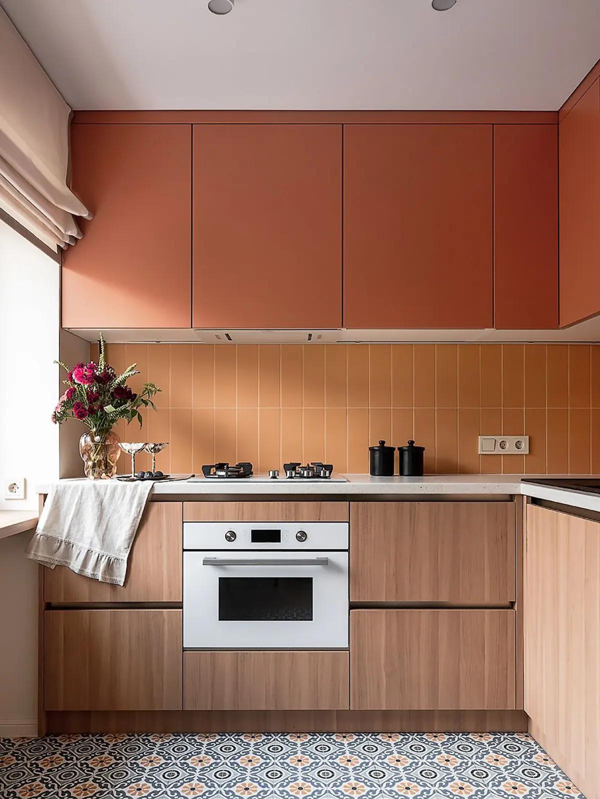Кухня с терракотовыми шкафами, оранжевым фартуком, белой духовкой и узорчатым полом