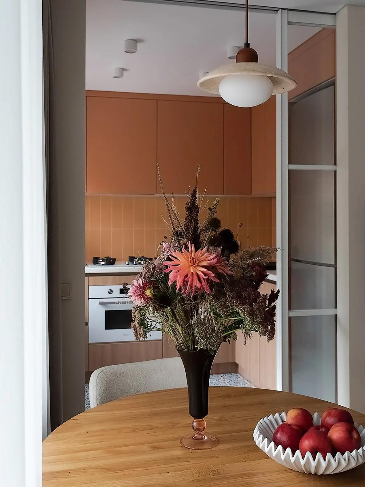 Букет цветов на деревянном круглом столе и тарелка с фруктами