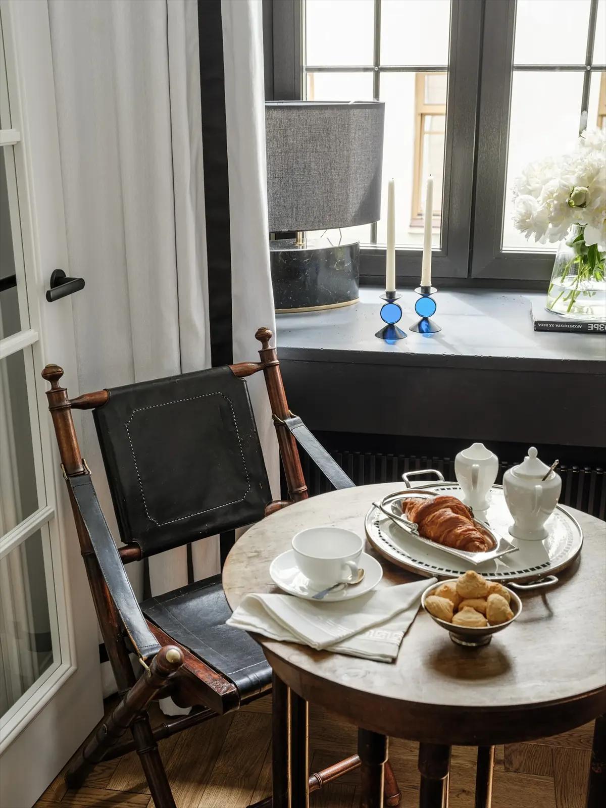 Маленький круглый стол с завтраком: круассан, чай, печенье