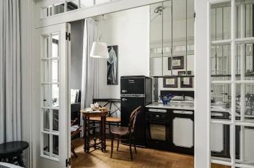 Вид через межкомнатные открытые двери на компактную кухню с черной техникой