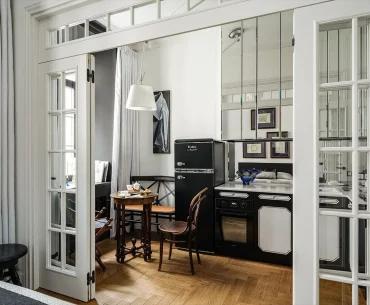 Вид через межкомнатные открытые двери на компактную кухню с черной техникой