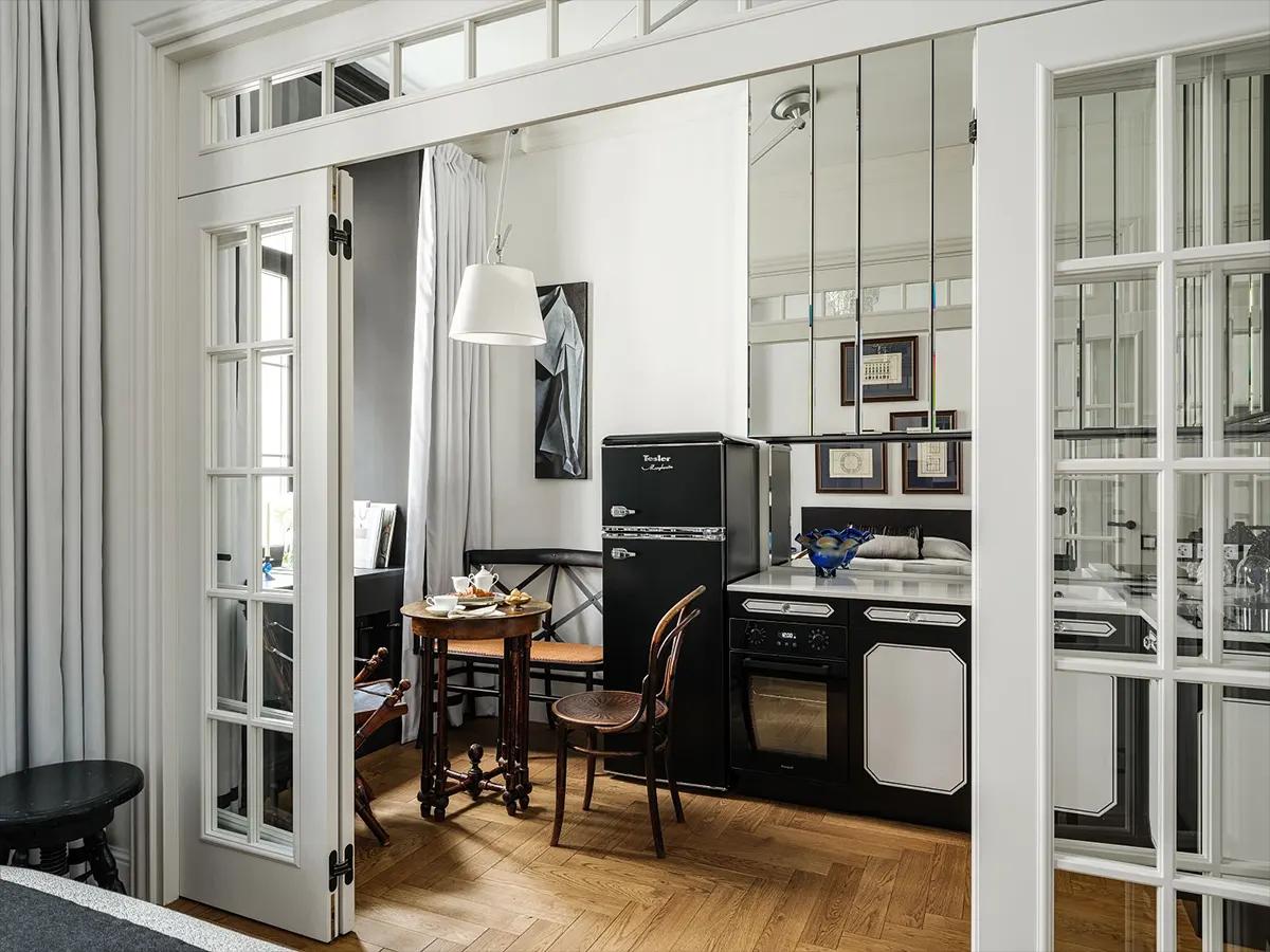 Вид через межкомнатные открытые двери на компактную кухню с черной техникой