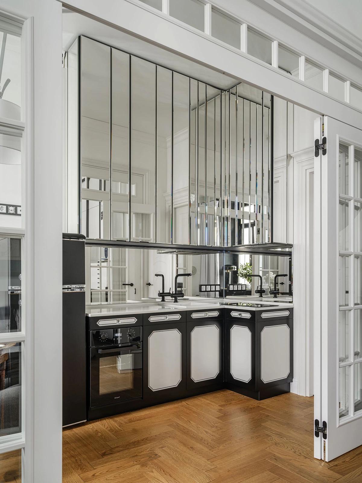 Вид на кухонный гарнитур в черно-белых тонах с зеркальными шкафами и фартуком