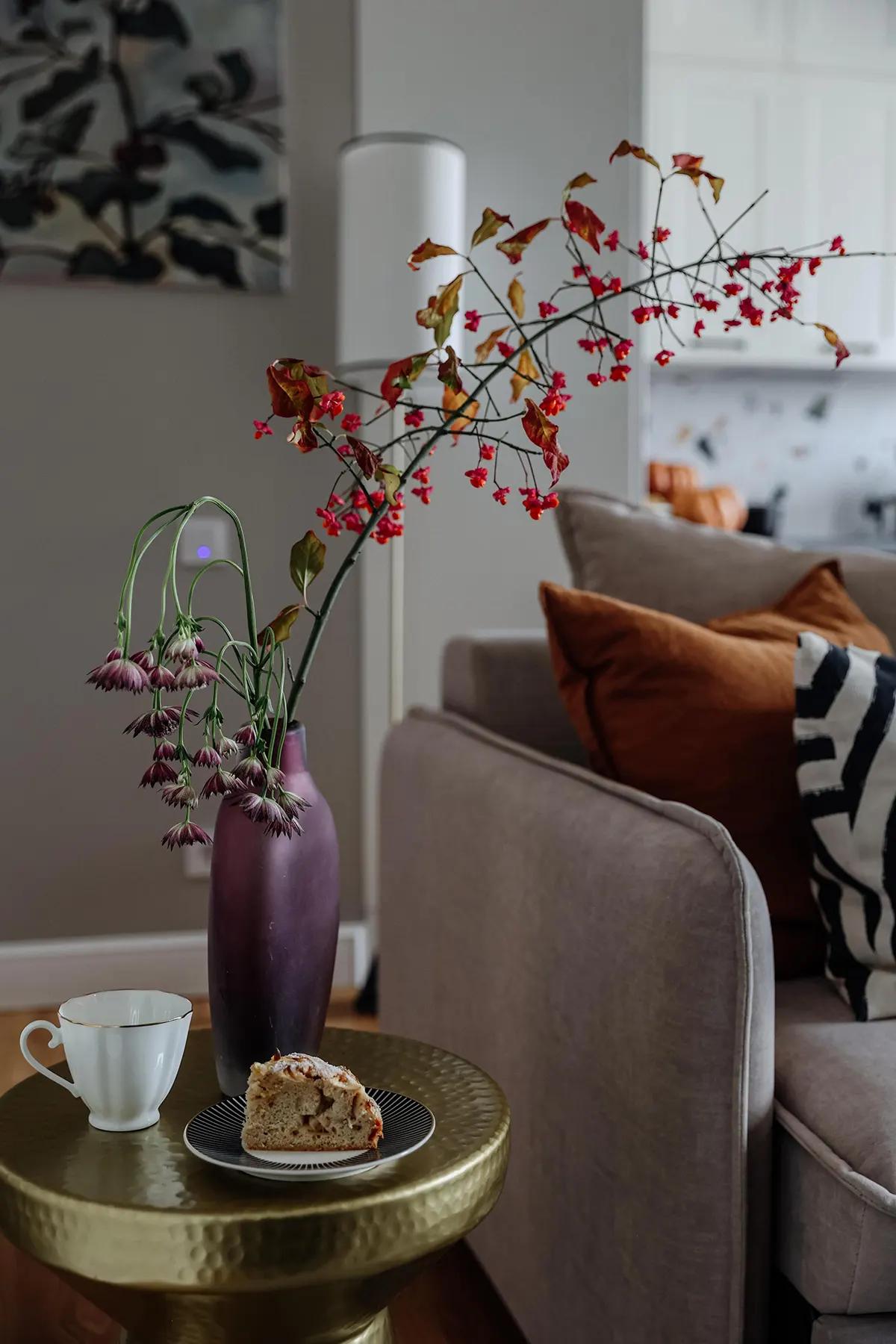 Столик с куском пирога, чашкой и фиолетовой вазой с цветами
