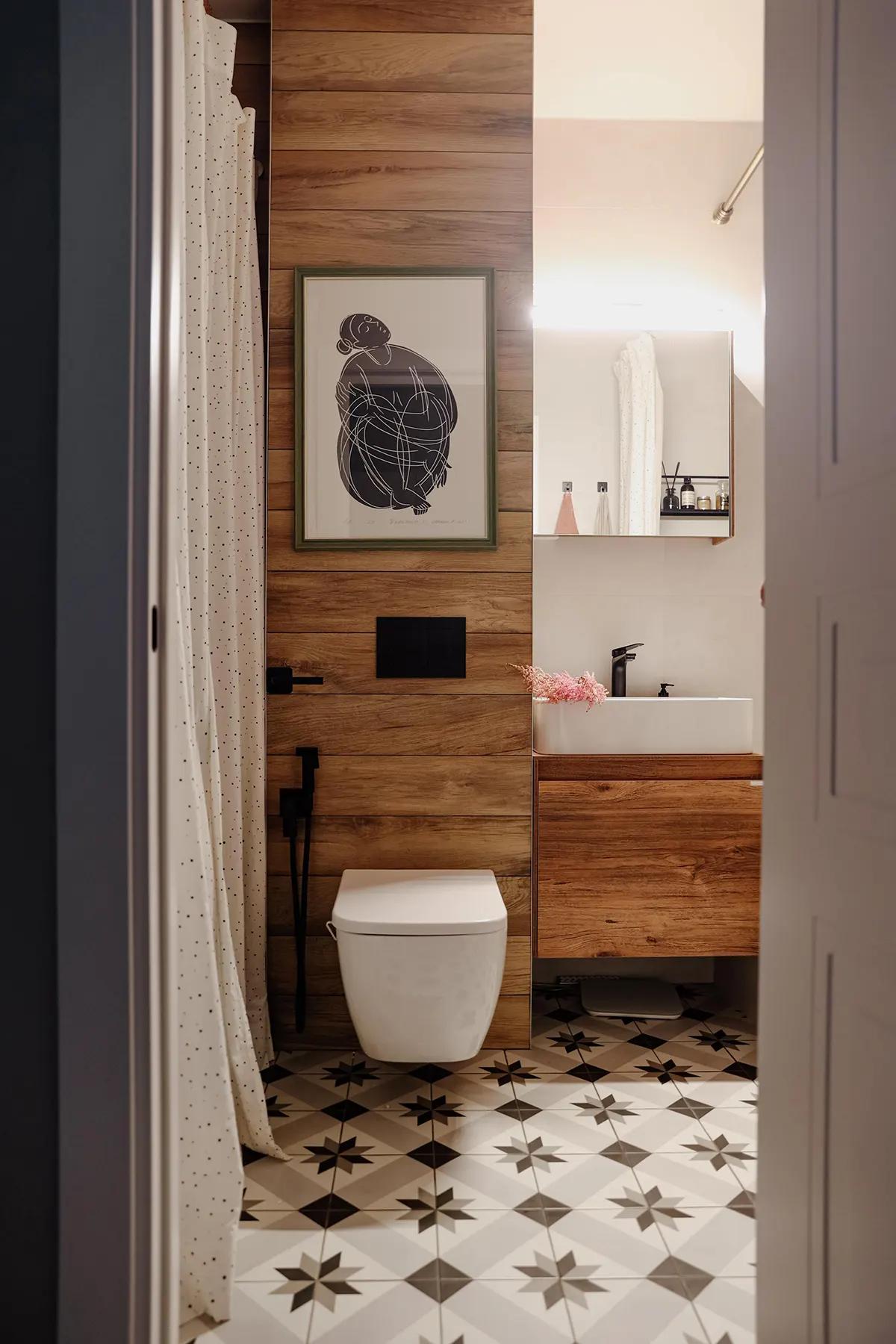 Ванная с белым унитазом, раковиной, зеркалом, картиной и узорчатым полом