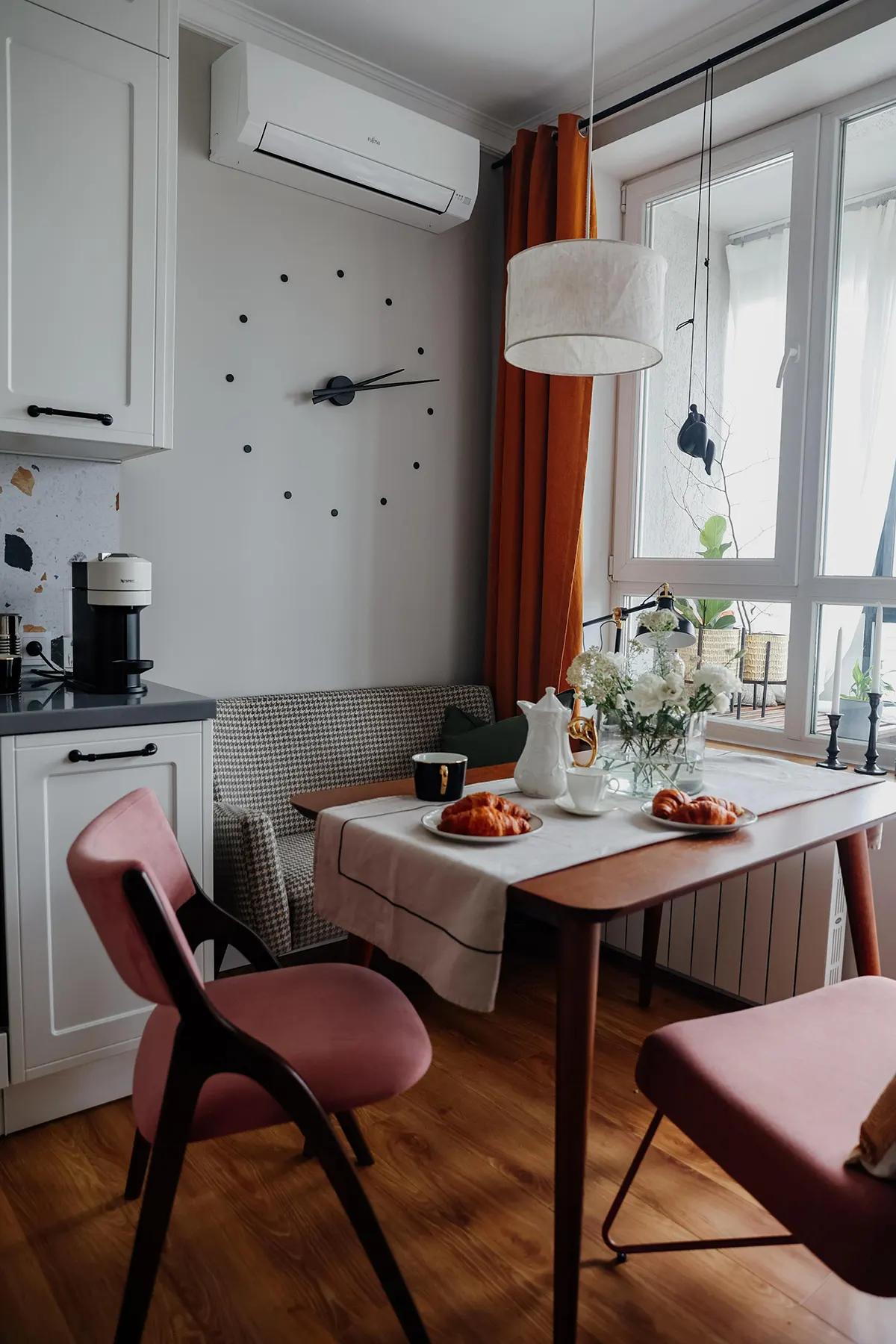 Кухонный стол с круассанами, кофе и цветами. Розовые стулья, оранжевые шторы