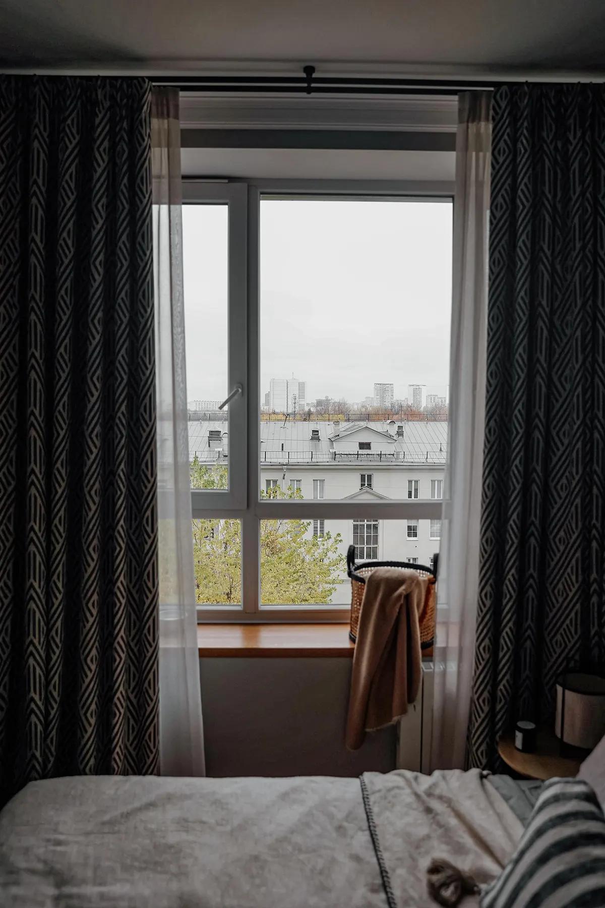 Окно с геометрическими шторами и видом на город