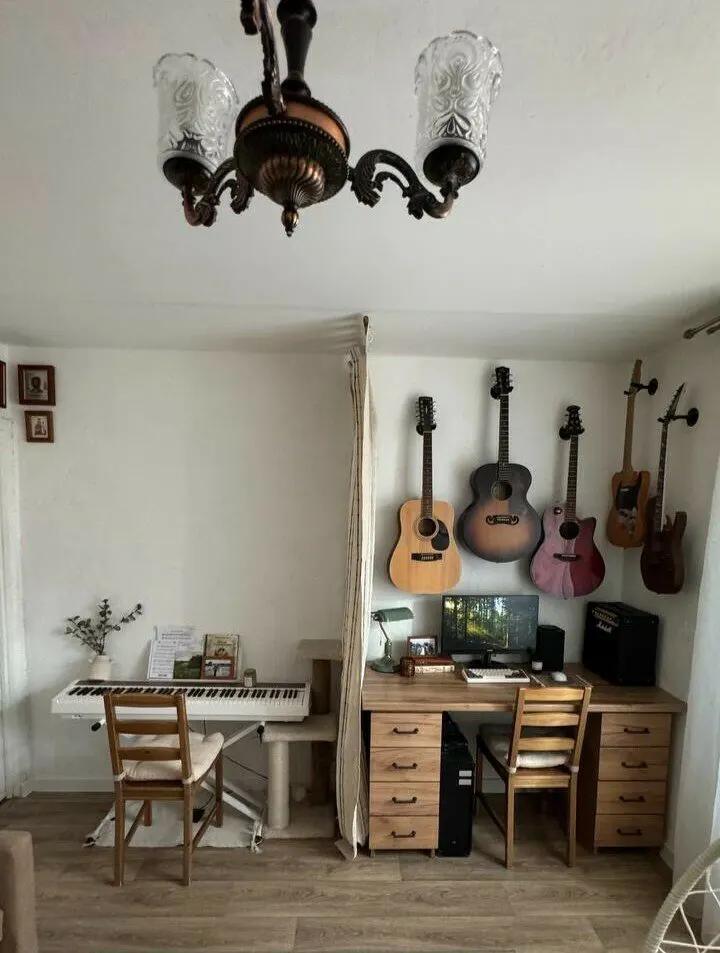 Две зоны в гостиной: творческая с пианино и рабочая с компьютером и столом. Над столом подвешены гитары