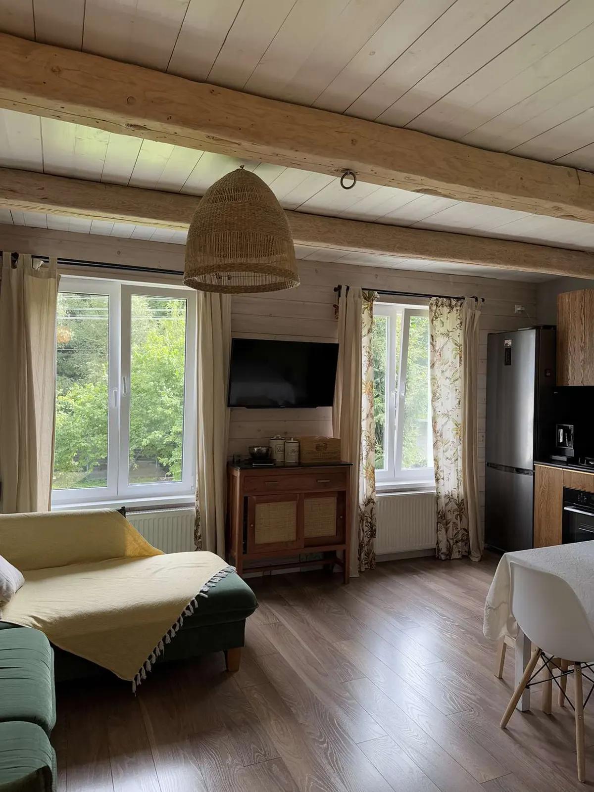 Просторная кухня-гостиная в доме с деревянными стенами и двумя пластиковыми окнами