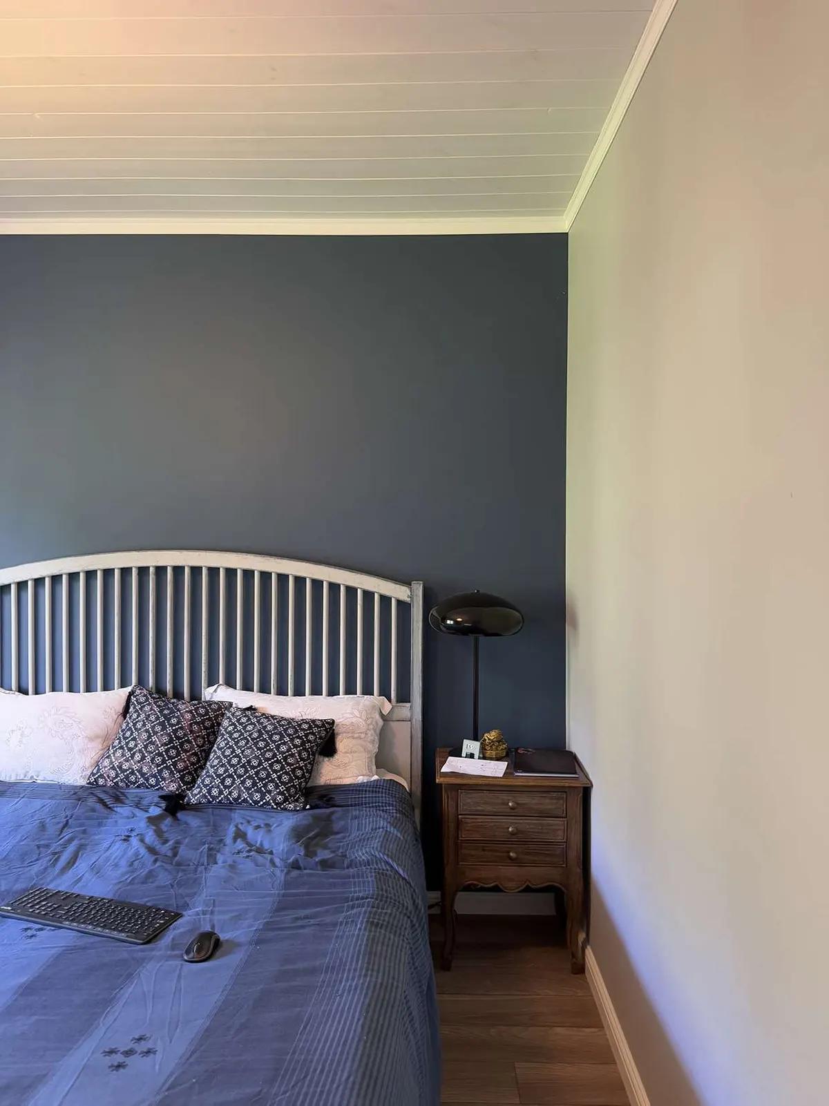 Угол спальни с прикроватной тумбочкой и черной глянцевой лампой