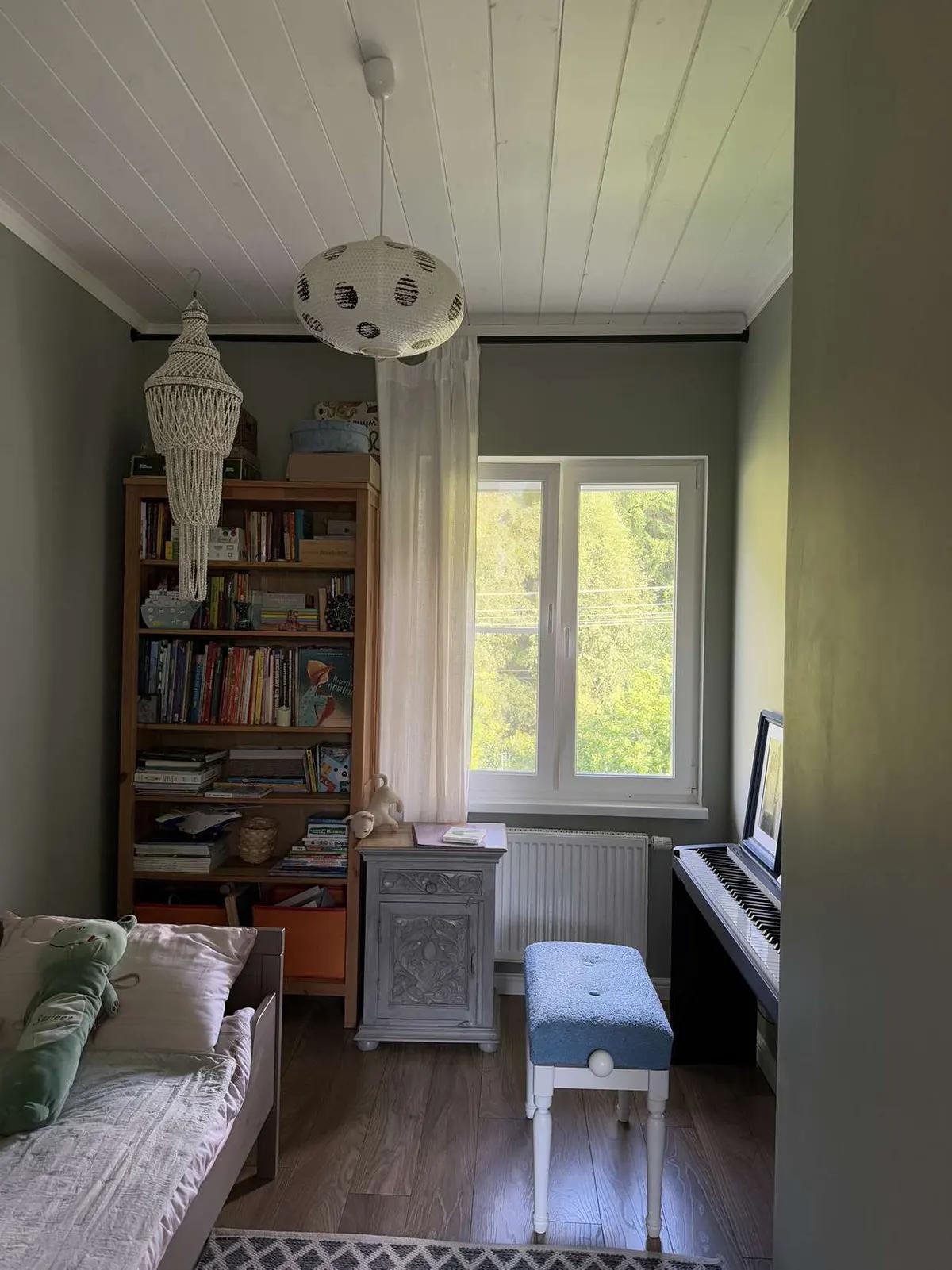 Детская комната с книжным шкафом, пианино, табуретом и кроватью