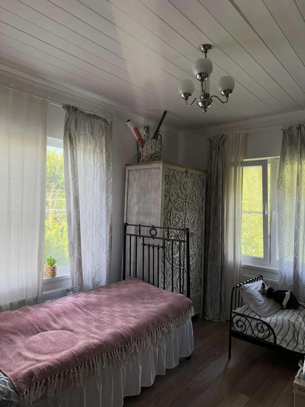 Комната с металлической кроватью и резным шкафом