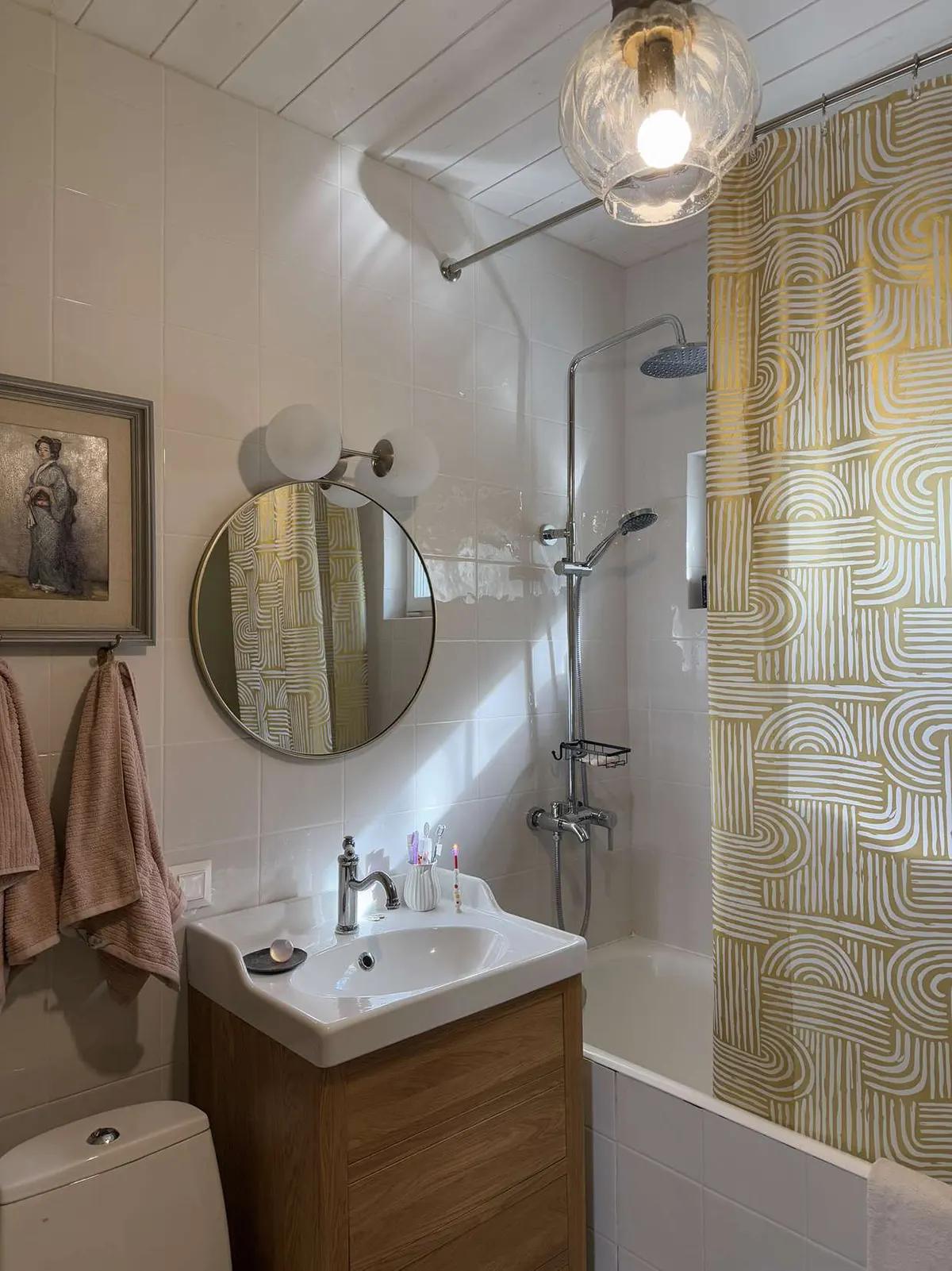 Ванная с круглым зеркалом, картиной, розовыми полотенцами, раковиной и узорчатой шторкой