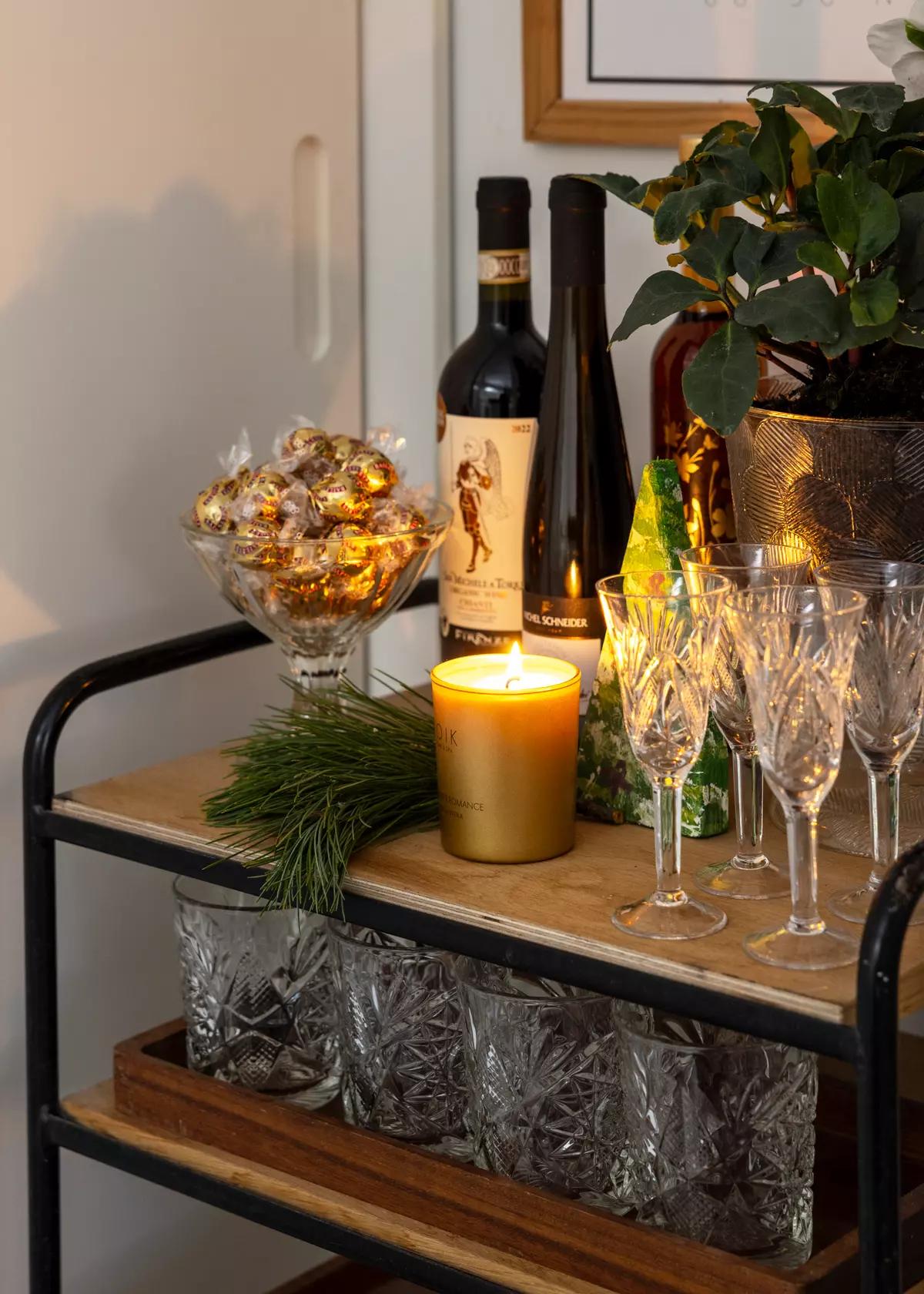 Барный столик с бутылками вина, конфетами в чаше, золотой свечой, еловой веткой
