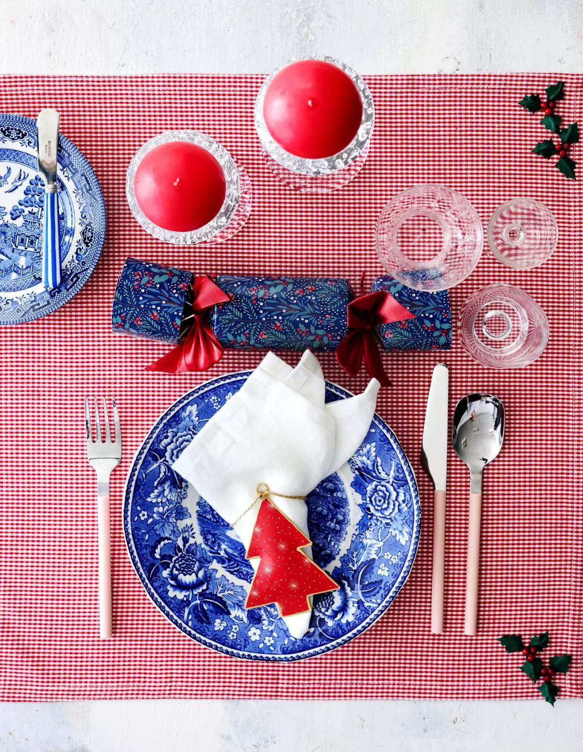Рождественская сервировка на красной клетчатой скатерти с синей цветочной тарелкой