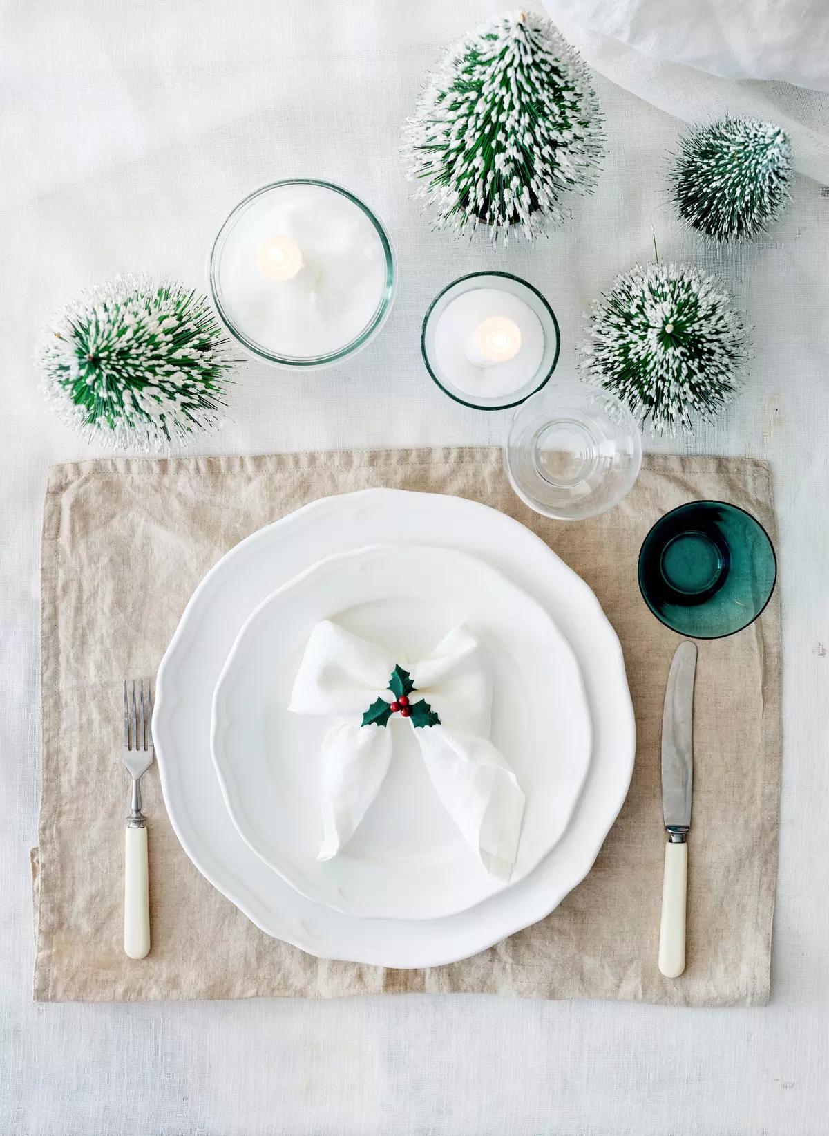 Уютная сервировка с бежевой салфеткой, белыми тарелками, свечами