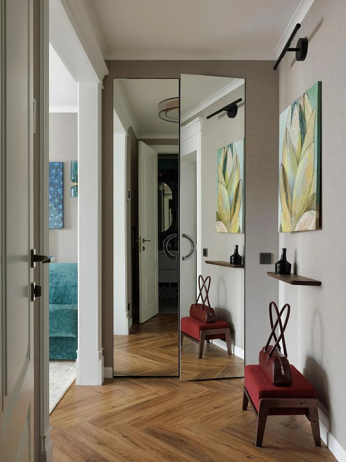 Интерьер прихожей, паркет елочкой, шкаф с зеркальными дверями в полный рост, темно-красный пуфик отражается в зеркале