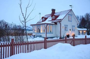 Заснеженный дом с красной крышей и белым фасадом в Финляндии