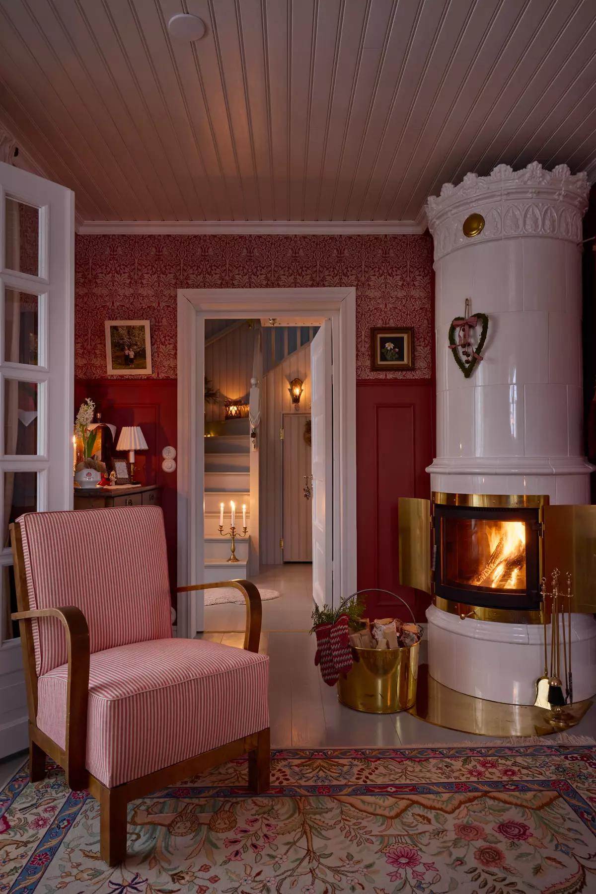 Гостиная с винтажным креслом в красно-белую полоску, большой изразцовой печью и латунным ведром для дров