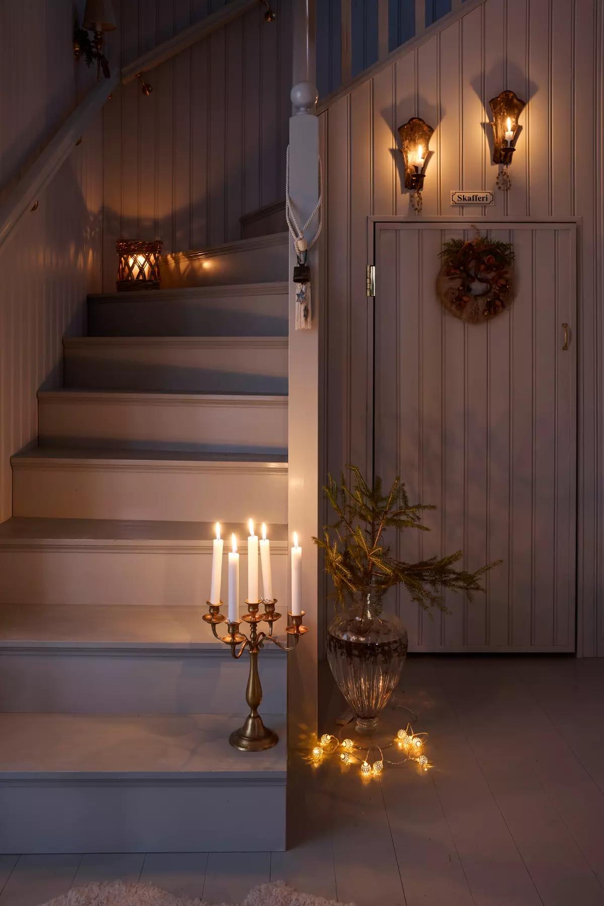 Лестница в финском доме, ведущая на второй этаж, украшенная светильниками, гирляндой, канделябром 